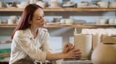 A pretty woman looking involved while painting the pot