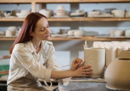A pretty woman looking involved while painting the pot