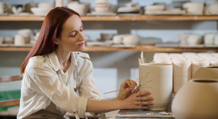 A pretty woman looking involved while painting the pot